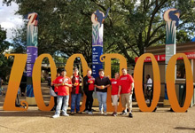 People standing before a Zoo Boo sign.