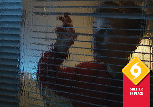 A young boy looks out a window at a dark, rainy scene