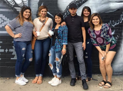 Five female students and one male student pose near street art