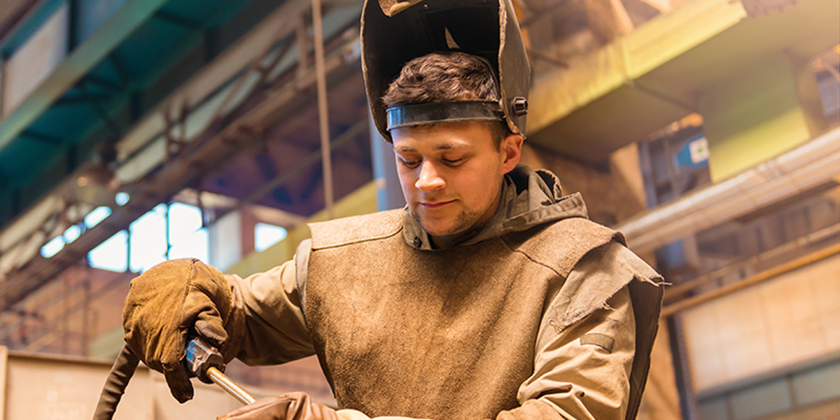 A young man in welding gear preparing to weld.