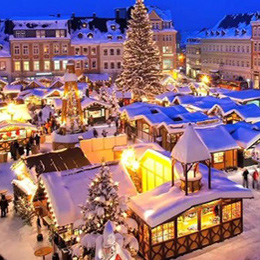 Christmas scene of a village covered in snow, with Christmas lights and a large outdoor Christmas tree