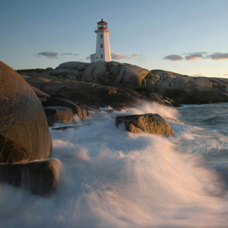 A lighthouse with waves crashing on a rocky shore